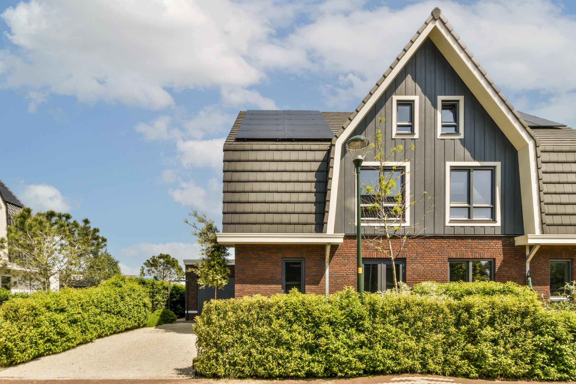 a-brick-house-with-a-grey-roof-and-a-driveway-BLSGHB6